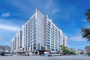 Un hôtel à plusieurs étages, doté d’un design moderne, avec une entrée imposante et un espace de stationnement situé à l’avant.
