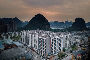 A high-rise residential building with multiple floors, surrounded by a dense urban area and mountains in the background. - Yake Hotel (Jingxi)