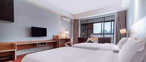 A hotel room with two beds, a TV, a desk, and a balcony with a view.