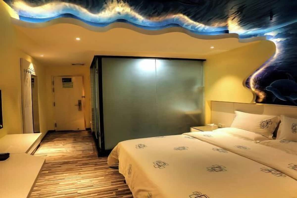 Quarto de hotel com uma cama, mesa de cabeceira, espelho, porta e parede com um design de teto singular.