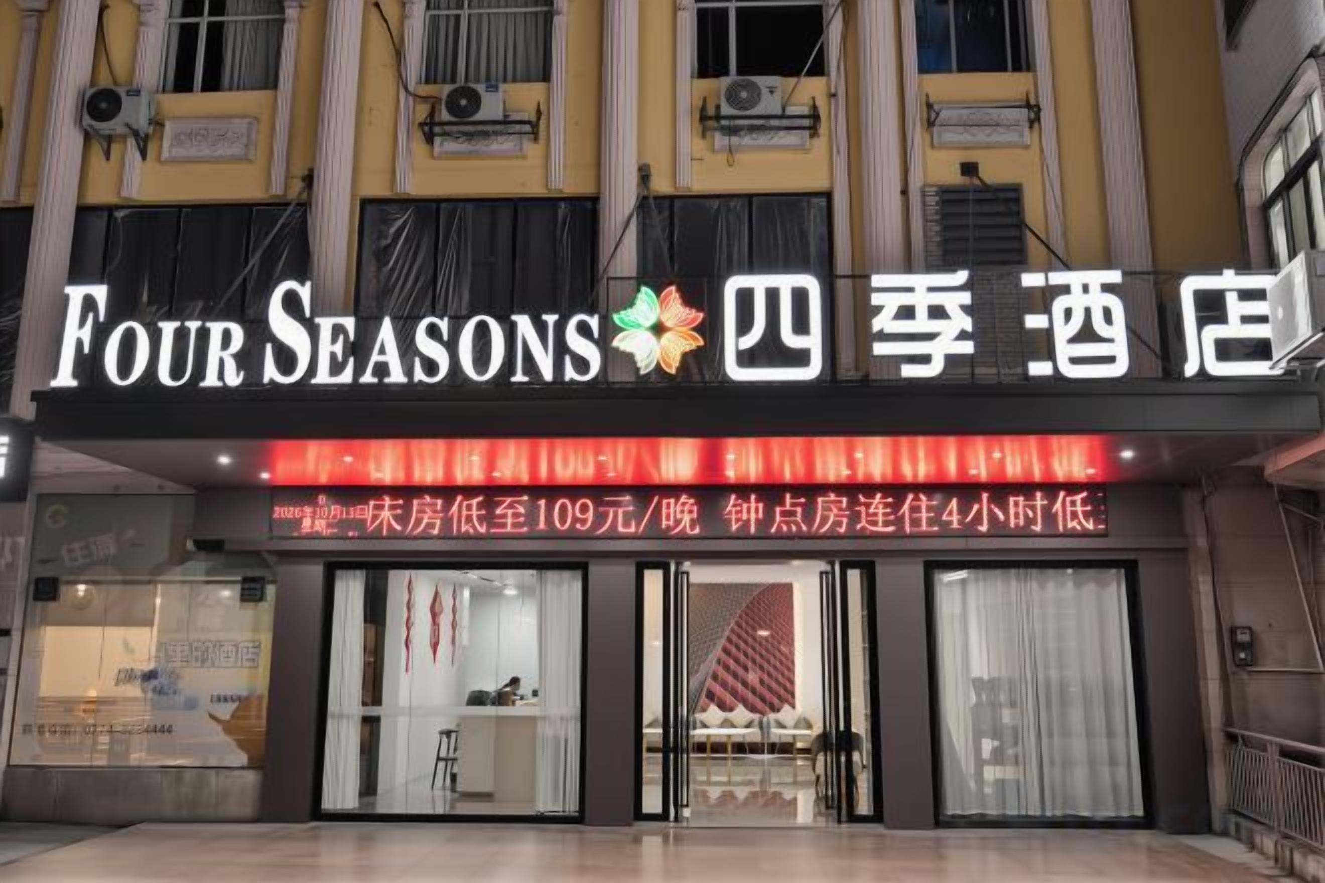 Um hotel com uma placa exibindo 'Four Seasons' e caracteres chineses.