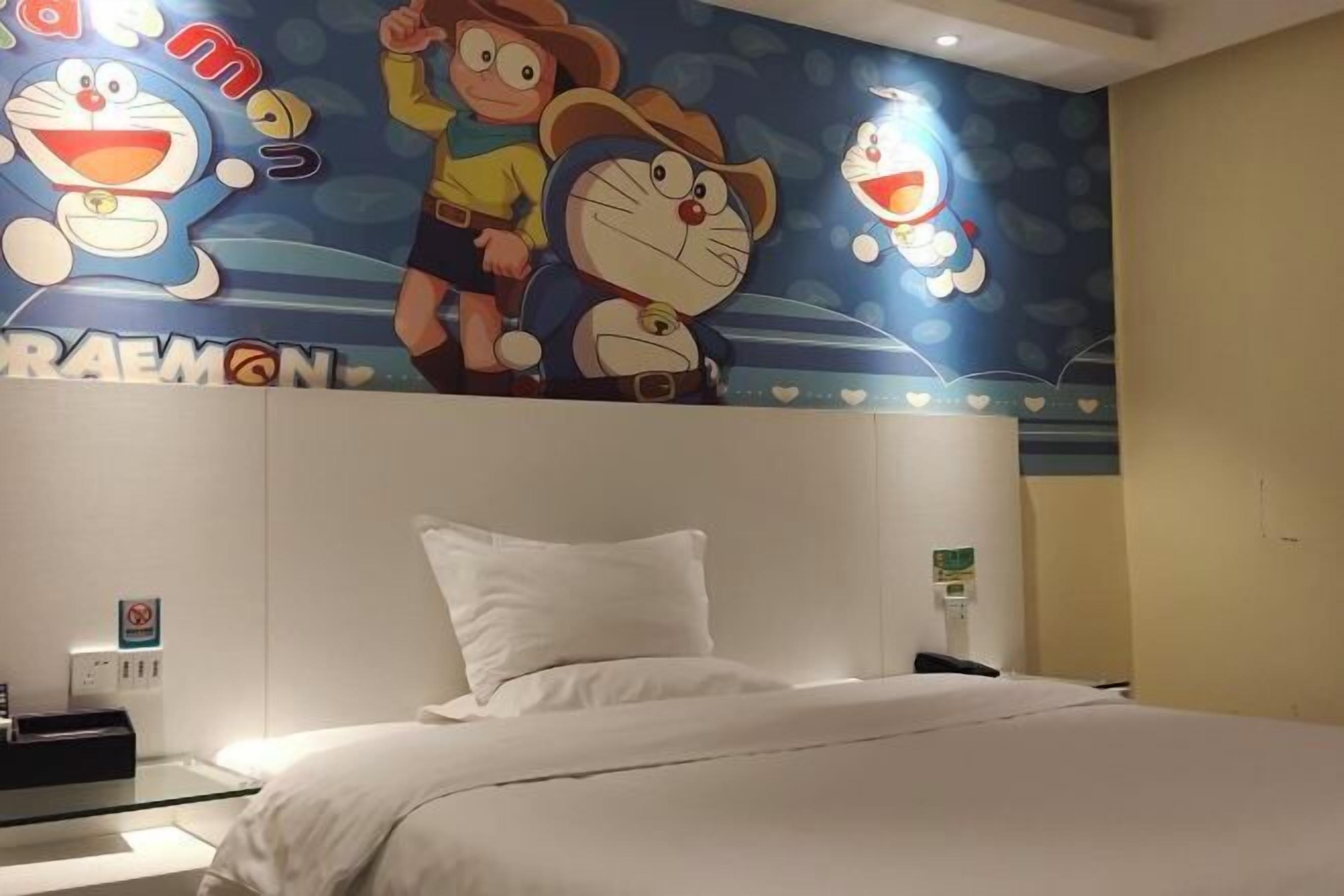 A hotel room with a bed, a wall with cartoon characters, and a sign that says "RAEMON".