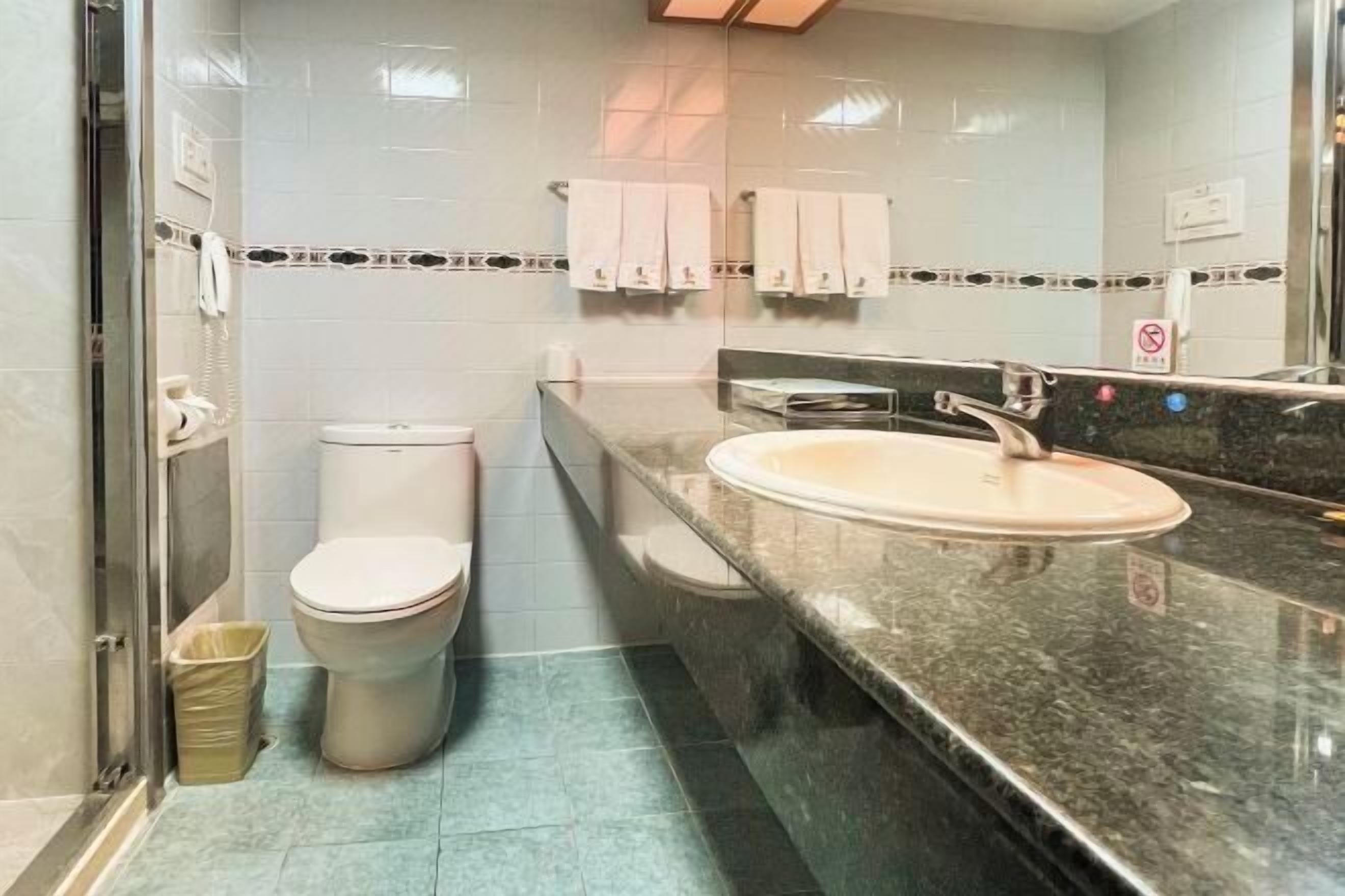 A bathroom with a toilet, sink, and shower area.