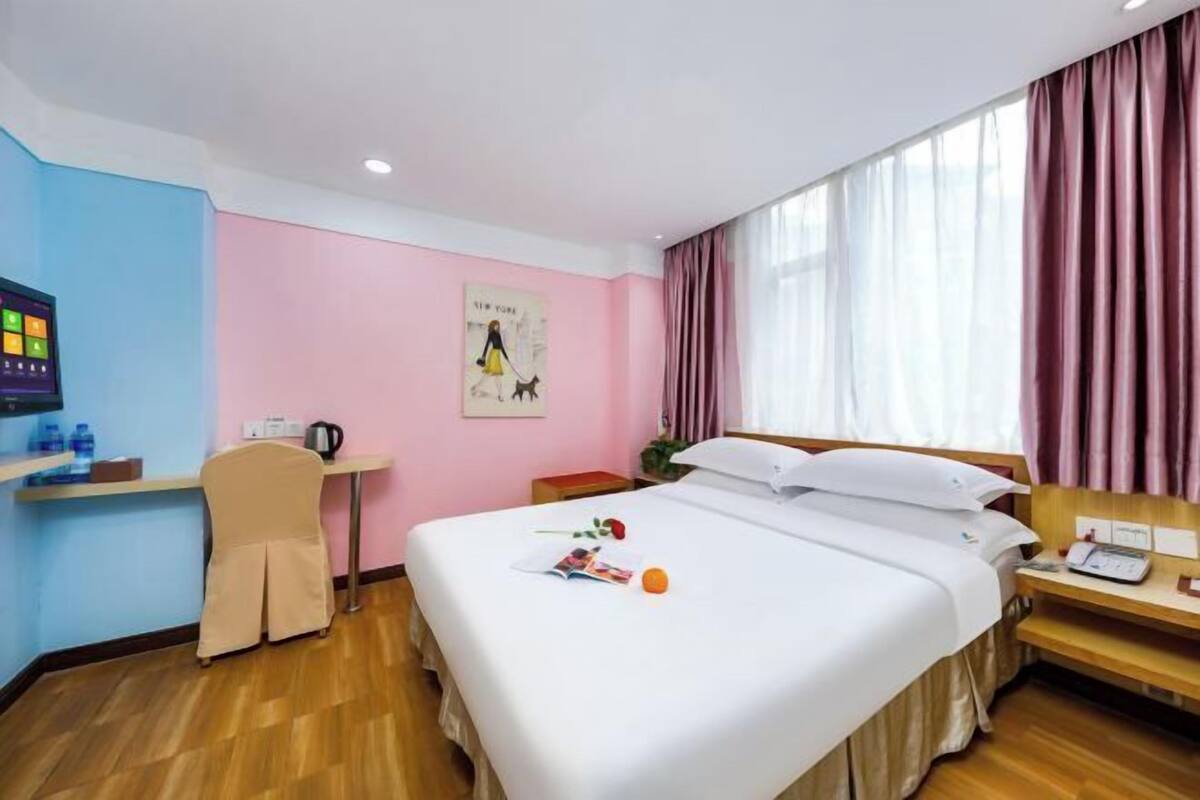 Una habitación de hotel con cama, mesita de noche y escritorio con silla.
