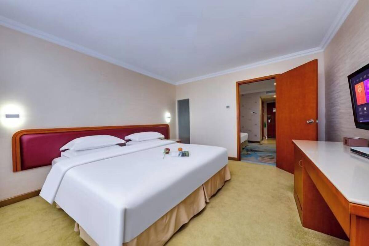 Una habitación de hotel con una cama, un escritorio y un televisor.