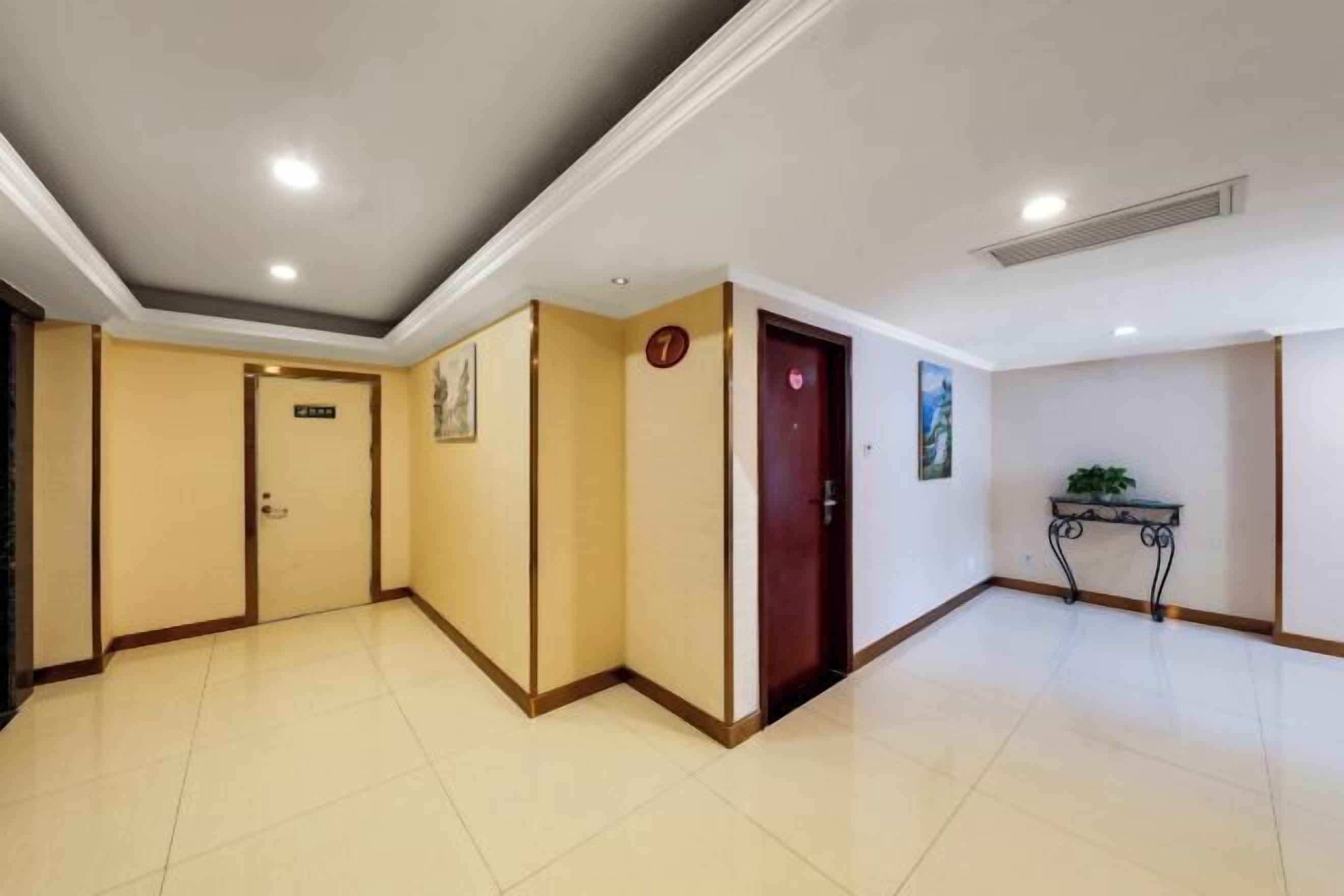 A hotel corridor with cream-colored walls, a tiled floor, and a door marked with the number 7.
