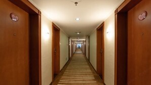 A hotel corridor with wooden doors, a carpeted floor, and a ceiling light. - L Hotel Zhuhai Gongbei Port Qinglv Road (Zhuhai)