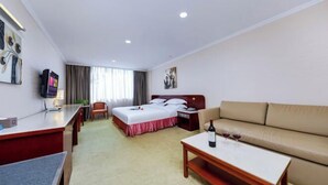 A hotel room with a bed, a sofa, a desk, and a TV. - L Hotel Zhuhai Gongbei Port Qinglv Road (Zhuhai)