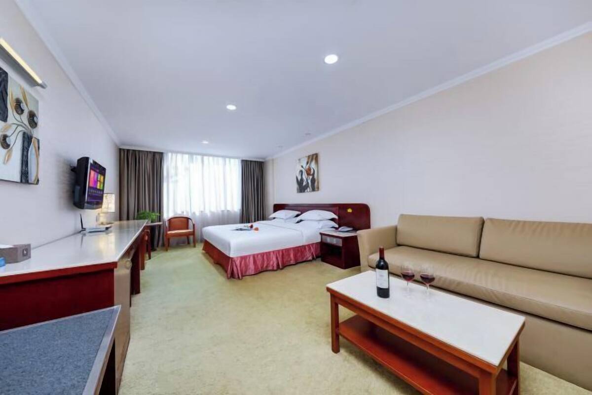 Una habitación de hotel con cama, sofá, escritorio y televisor.