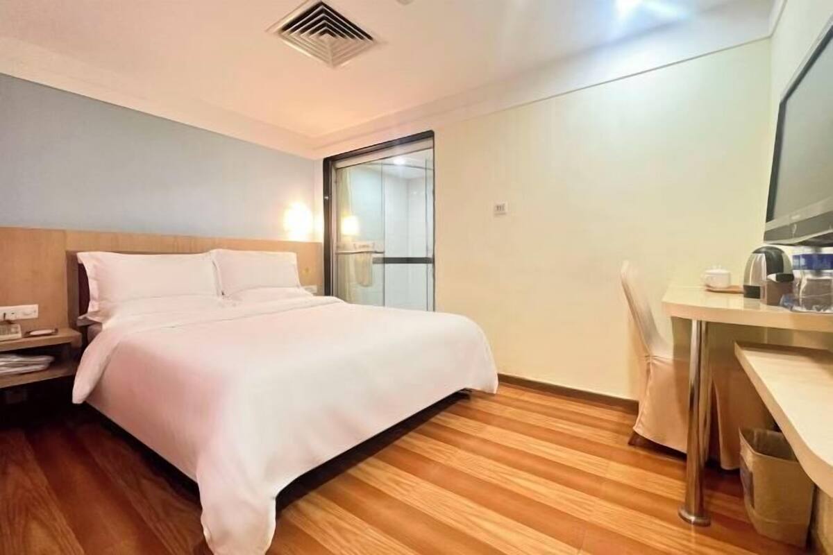 Una habitación de hotel con cama, escritorio, silla y espejo.