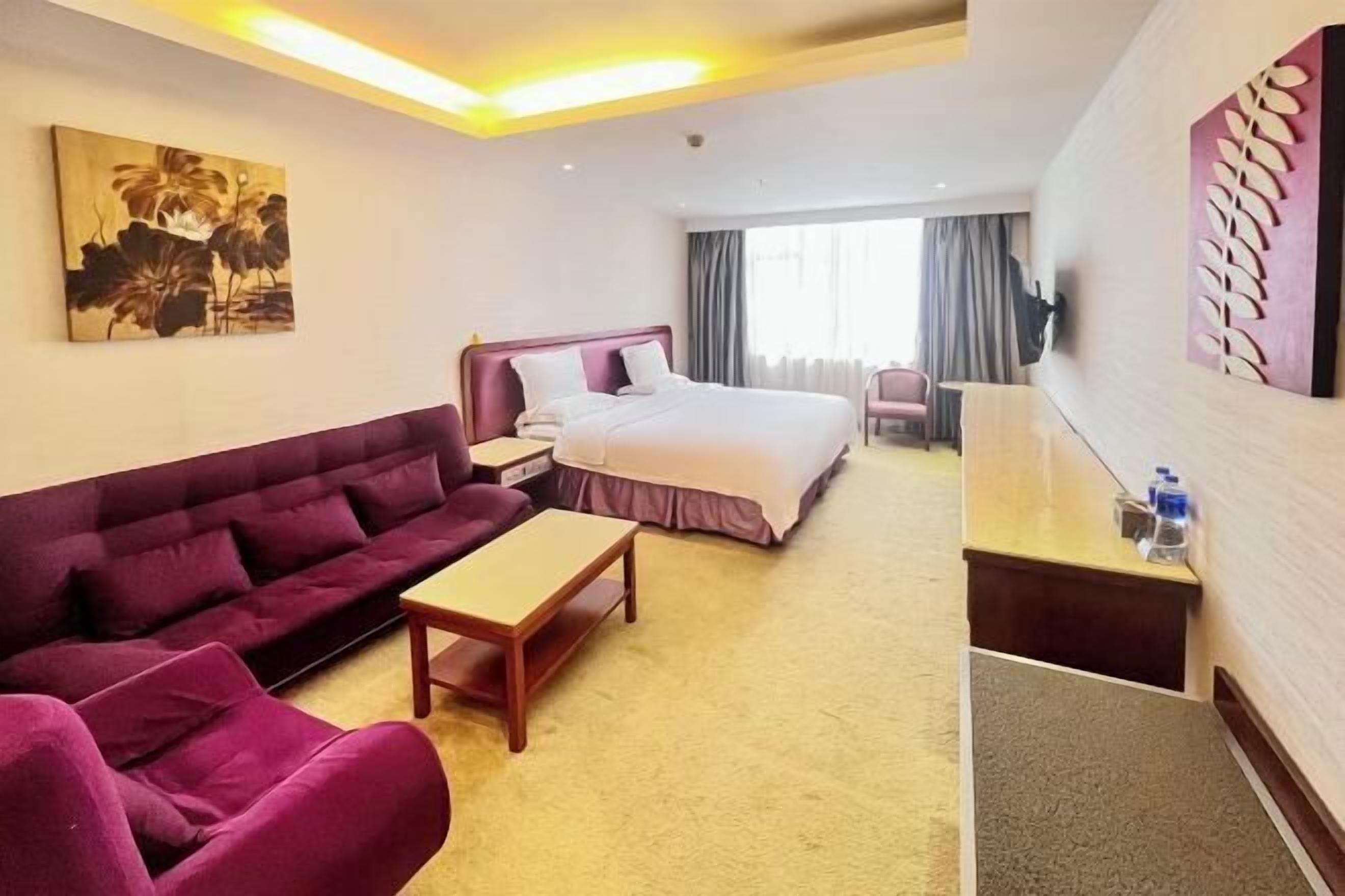 Een hotelkamer met een bed, een bank, een bureau en een schilderij aan de muur.