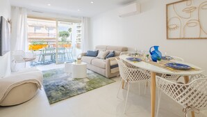 A modern living room with a sofa, dining table, and chairs. There is a balcony with outdoor furniture. - Stylish 2-Br Apartment Steps from the Croisette (Cannes)