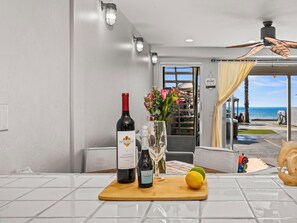 A kitchen with a wine bottle, a glass, and a lemon on a cutting board. - BEACHFRONT COTTAGE LOWER UNT ON THE STRAND IN OCEANSIDE, TWO-BED AND ONE-BATH (Oceanside)