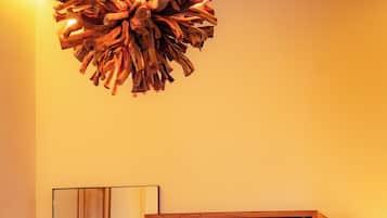 Uma sala de jantar com uma mesa redonda, duas cadeiras, um armário de madeira e um lustre de design exclusivo.