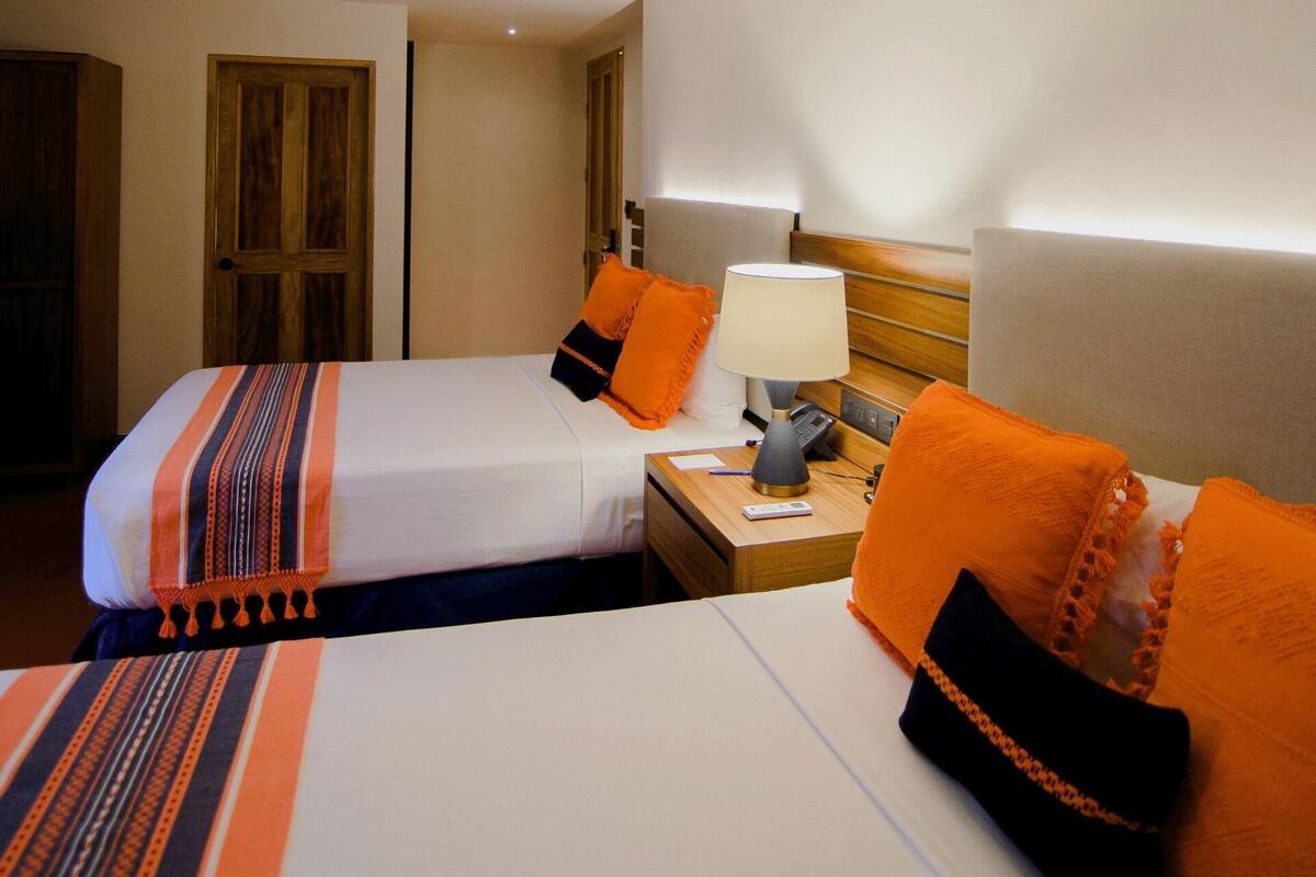 Une chambre d’hôtel avec deux lits, une table de chevet, une lampe et un téléphone.