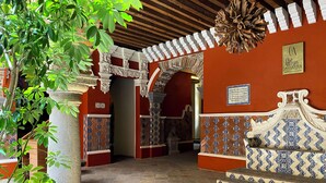 An interior corridor with red walls, patterned tile flooring, and a wooden ceiling. - Casa Azulai Puebla Hotel Boutique (Puebla)