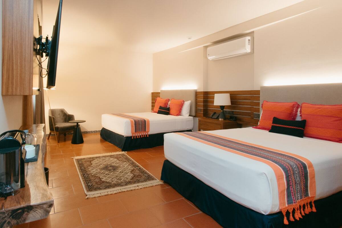 Une chambre d’hôtel avec deux lits, un bureau, une chaise, une télévision et un appareil de climatisation.
