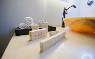 Una encimera de baño con un lavabo, un cuenco grande y varios artículos de aseo, incluyendo un kit de afeitar.
