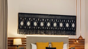 A hotel room with a bed, bedside tables, a tray with breakfast items, and a decorative wall hanging. - Casa Azulai Puebla Hotel Boutique (Puebla)