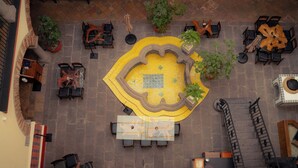 An aerial view of a courtyard with a central fountain, surrounding seating areas, and potted plants. - Casa Azulai Puebla Hotel Boutique (Puebla)