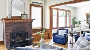 Ein Wohnzimmer mit Kamin aus Backstein, einem blauen Sofa und einem großen Fenster.