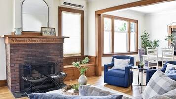 A living room with a brick fireplace, a blue sofa, and a large window.