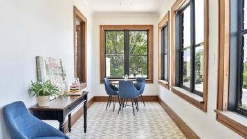 A dining area with a table and chairs, a potted plant, and a painting on the wall.