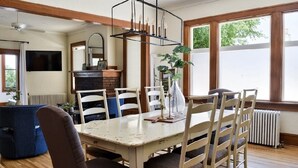 Ein Essbereich mit einem weißen Tisch, Holzstühlen und einer hängenden Lampe.