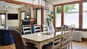 A dining area with a white table, wooden chairs, and a hanging light fixture.