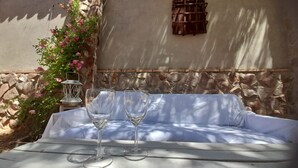 A white outdoor seating area with two empty wine glasses and a lantern.