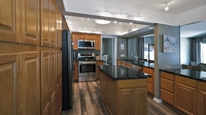 A modern kitchen with wooden cabinets, stainless steel appliances, and a black granite countertop.