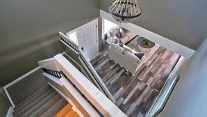 Un escalier menant à un espace de vie comprenant un canapé, une table basse et un lustre.