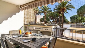 A balcony with a table set for dining, overlooking a pool and palm trees. - Lovely apartment for 4 people with WIFI, A/C, TV and balcony (Le Lavandou)