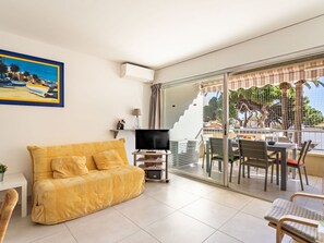 Relax in this stylish living room with a sofa, flat-screen TV, and a beautiful painting. Enjoy the view from the sliding glass door leading to an outdoor dining area.