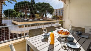 A balcony with a table set for breakfast, overlooking a courtyard with trees and buildings. - Lovely apartment for 4 people with WIFI, A/C, TV and balcony (Le Lavandou)