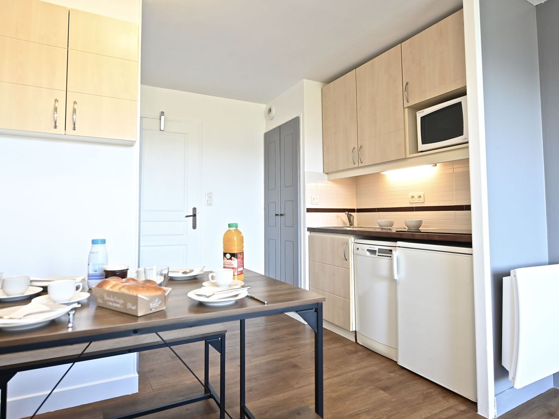 A compact kitchen with wooden cabinets, a microwave, and a dishwasher.