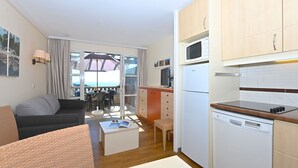 A compact living space with a sofa, a dining table, and a kitchen area including a microwave and dishwasher. - Cosy apartment for 6 people with WIFI, A/C, pool, TV, terrace and pets allowed (Saint-raphaël)