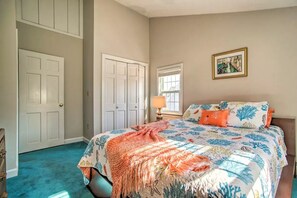 Quarto com cama, mesa de cabeceira, janela e porta.