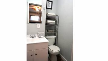 Een bad/douchecombinatie, handdoeken, zeep, toiletpapier