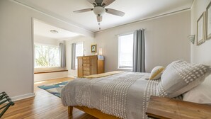 Un dormitorio con cama de madera, ventilador de techo y vistas al exterior.