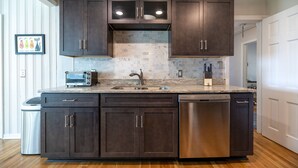 Una cocina moderna con armarios oscuros, lavavajillas integrado y un salpicadero de azulejos.