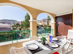 Balcón con mesa lista para comer, con vista a una zona residencial con edificios y árboles.