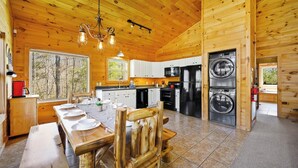 Interior de una cabaña de madera con comedor, cocina y dos lavadoras.