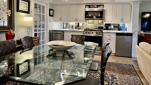 A modern kitchen with white cabinetry, stainless steel appliances, and a glass dining table. - 20 minute walk to downtown and beach - Rehoboth Ave Extended (Rehoboth Beach)