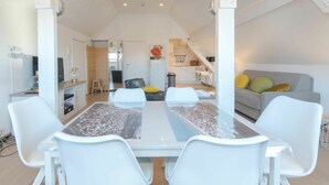 A modern, open-plan living space with a dining area, kitchen, and seating area. - Beautiful apartment for 4 people with WIFI, TV and pets allowed (De Haan)