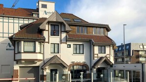 A two-story hotel with a modern design, featuring a balcony with seating and a glass enclosure. - Beautiful apartment for 4 people with WIFI, TV and pets allowed (De Haan)
