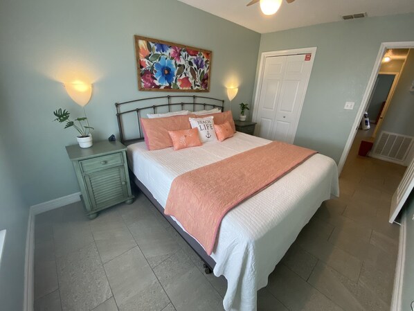 A bedroom with a bed, nightstands, a painting, and a door.