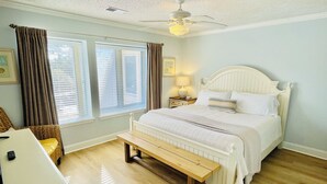 Ein Schlafzimmer mit einem Bett, einer Bank, einem Schreibtisch und einem Deckenventilator.