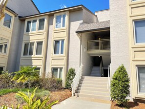 A multi-story residential building with a central staircase, balconies, and a landscaped garden area.
