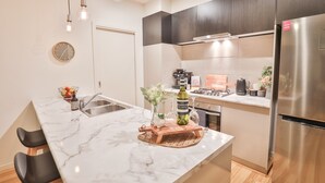 A modern kitchen with a marble countertop, stainless steel appliances, and a wooden island with a vase and bottle. - Modern 4 bedroom house with marina mooring, 2km from CBD (Mildura)